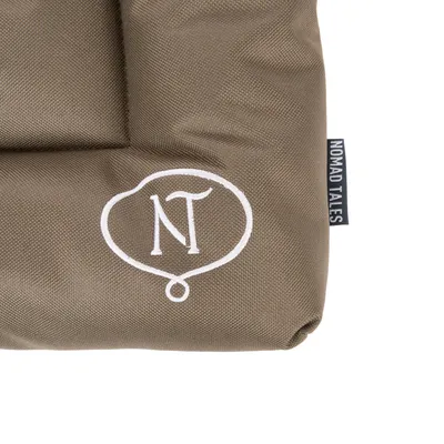 Nomad Tales logo na smeđoj tkanini s bijelim NT simbolom.