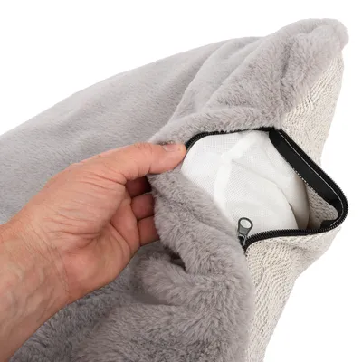 Hand öppnar grått, mjukt överdrag med dragkedja, vitt innermaterial synligt under.