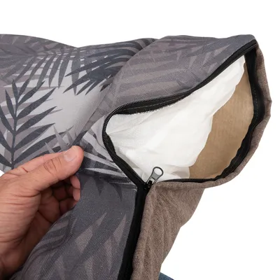 Närbild av avtagbart kuddfodral med dragkedja och tropiskt bladmönster. Inuti syns vit kudde av nätmaterial.