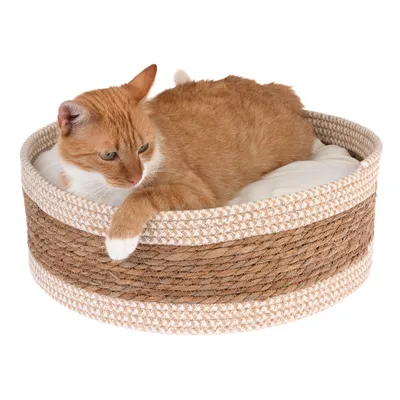 Panier rond en corde tressée beige et marron avec coussin blanc, chat roux et blanc allongé à l’intérieur. Matériaux visibles : corde, tissu.
