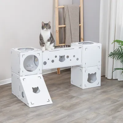 Модульный белый игровой домик для кошек из картона с несколькими входами и платформами. Кошка сидит на средней платформе.