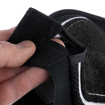 Close-up of a black hook-and-loop fastener being opened by a hand.