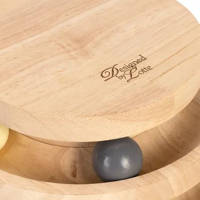 Jouet en bois avec inscription « Designed by Lotte », deux boules visibles, une grise et une jaune, dans une piste circulaire creusée dans la base.