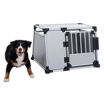 Metal transport box with grid door and sturdy construction, next to a sitting dog. Suitable for safe transport of pets.