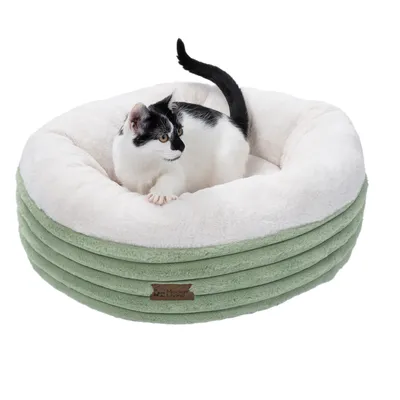 Rundes, gepolstertes Haustierbett in Grün und Weiss mit Modern Living Logo. Katze sitzt im Bett.