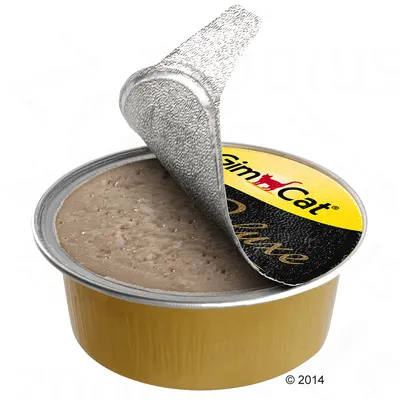 Avoin GimCat Deluxe -kissan märkäruokapurkki, kannen osa käännetty auki, näkyvissä ruskeaa tahnamaista sisältöä. Kelta-musta etiketti, jossa lukee 'GimCat' ja 'Deluxe'.