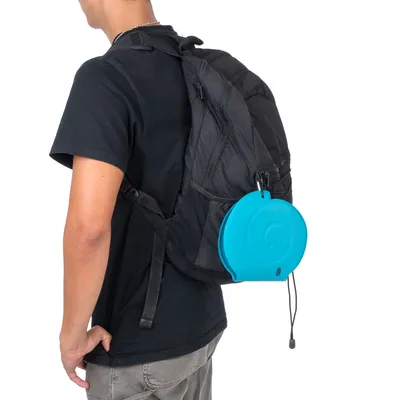 Homme portant un sac à dos noir avec une gamelle pliante bleue en plastique accrochée à l’extérieur du sac par un mousqueton.