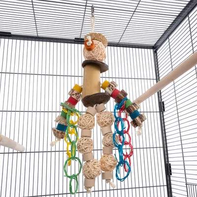 Игрушка для птиц из дерева, ротанга и цветных пластиковых колец, подвешенная в клетке. С веревочной подвеской и несколькими подвижными элементами.