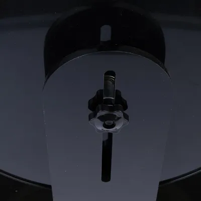 Schwarzer Einstellmechanismus mit Drehknopf und Schlitzen zur Anpassung, sichtbar auf einer glänzenden Oberfläche.