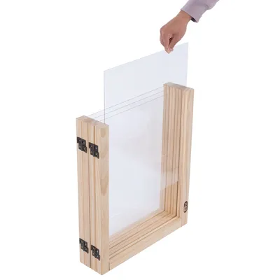 Houten frame met plexiglas inzet, hand toont het plaatsen van het plexiglas. Geschikt voor flexibele aanpassing of vervanging van materialen.