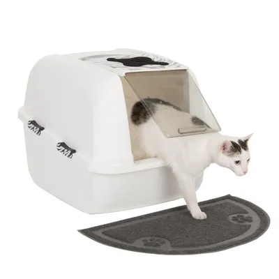 Witte kattenbak met klapdeksel en zebrapatroon, kat stapt op grijze mat met pootafdrukken.