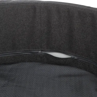 Nahaufnahme eines dunkelgrauen Stoffbezugs mit sichtbarem Reißverschluss, der geöffnet ist und die innere Polsterung zeigt.