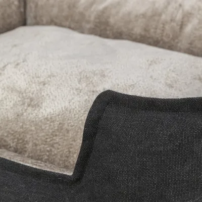 Nahaufnahme eines beigen Polsters mit schwarzem Stoffrand, Materialstruktur sichtbar.