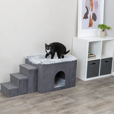 Graues Katzenmöbel mit Treppe, Höhle und weicher Liegefläche. Schwarze Katze steht oben auf der Liegefläche.
