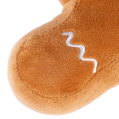 Gros plan sur une peluche marron en tissu avec couture blanche en zigzag visible.