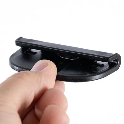 Main tenant une pièce en plastique noir de forme arrondie avec rebord, aucun texte ou marque visible.
