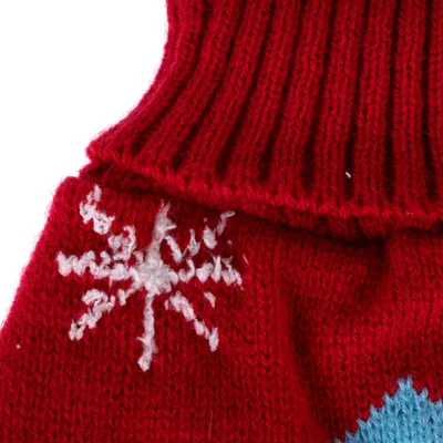 Roter gestrickter Stoff mit weissem Schneeflockenmuster und blauem Akzent. Detailaufnahme eines Designs.