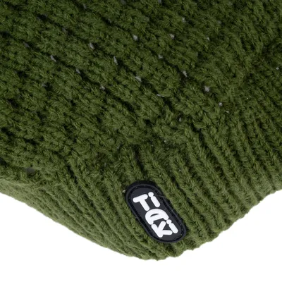 Gros plan sur un tricot vert avec étiquette visible portant le nom de la marque TIAKI.