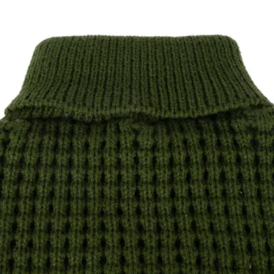 Gros plan sur un col roulé en maille verte, matière tricotée à larges mailles visibles. Aucun logo ni texte apparent.