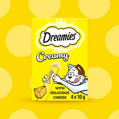 Dreamies Creamy with delicious cheese, 4 x 10g sachets shown on yellow packaging with cartoon cat and cheese illustration.