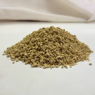 Close-up van los, lichtbruin granulaat op een witte ondergrond. Productdetails niet zichtbaar.