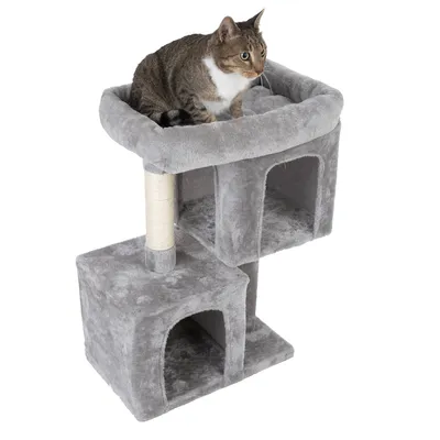 Rascador gris con dos cuevas, una superficie para tumbarse arriba y un poste rascador de sisal. Gato sentado en la superficie superior.
