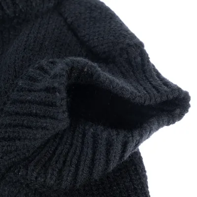 Gros plan sur un vêtement en maille noire, texture tricotée visible, ouverture côtelée. Matière : tissu.
