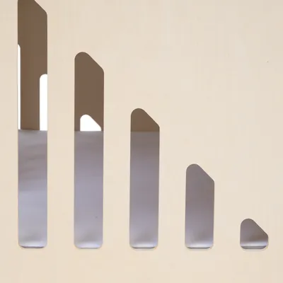 Detailansicht eines Holzdesigns mit vertikalen, abgerundeten Ausschnitten in verschiedenen Grössen.