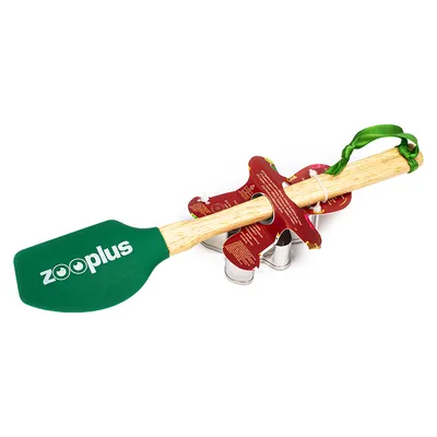 Zooplus espátula verde com cabo de madeira, combinada com etiqueta de produto vermelha e forma de metal. Marca visível na espátula.