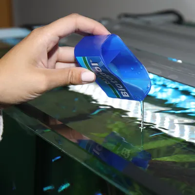 Hand giesst Biocool Flüssigkeit in ein Aquarium zur Wasserpflege.