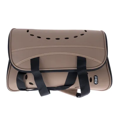 Sac de transport beige Tiaki avec poignées noires, plusieurs trous d’aération visibles sur le dessus et le côté, logo Tiaki en bas à droite.