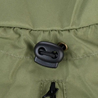 Gros plan sur un cordon de serrage noir avec bloqueur en plastique sur tissu vert, couture visible. Matériaux : tissu et plastique.