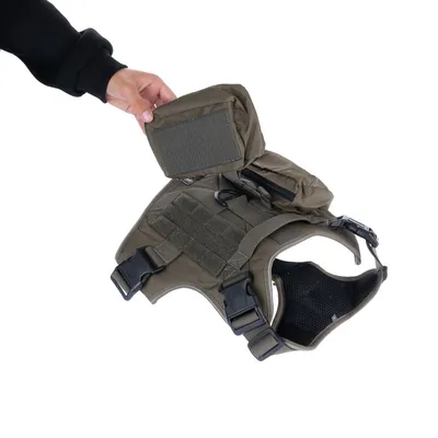 Olivegrünes Hundegeschirr mit abnehmbarer Tasche, verstellbaren Gurten und Klickverschlüssen. Hand zeigt die Tasche.