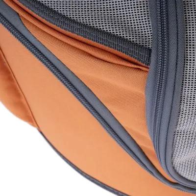 Detalhe de bolsa ou mochila em tecido laranja com fecho cinzento e rede cinzenta visível.