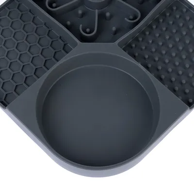 Gamelle en plastique gris foncé avec quatre compartiments de formes et textures différentes : alvéoles, picots, spirales et un bol rond lisse.