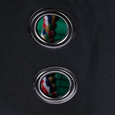 Gros plan sur deux œillets métalliques sur tissu noir, avec une corde multicolore visible à travers les ouvertures.