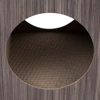 Close-up of a round entrance with brown wood look and an interior made of corrugated cardboard.