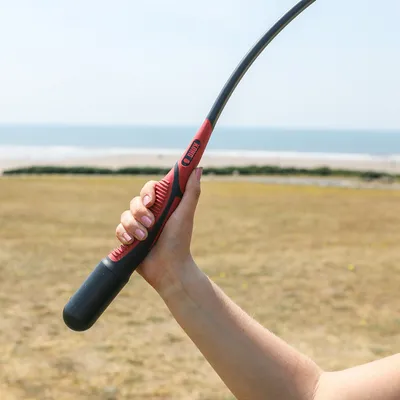 Hand holding a red and black throwing stick with the inscription 'KONG', suitable for throwing toys.