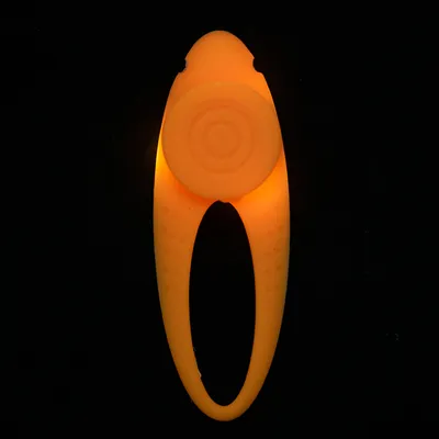 Lysande orange leksak med runda mönster och oval form, lämplig för mörka miljöer.
