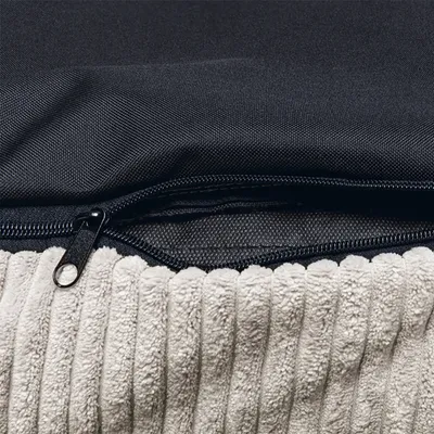 Close-up of a zip on a black fabric cover with a soft, ribbed beige surface.