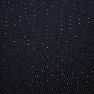 Surface en tissu noir avec petits points antidérapants régulièrement espacés, vue rapprochée du matériau.