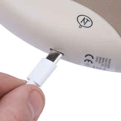 Primo piano di un cavo di ricarica USB-C inserito in un dispositivo con marchio CE e specifiche tecniche.