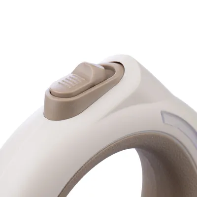 Primo piano di un interruttore beige-marrone su un'impugnatura ergonomica, probabilmente parte di un prodotto con funzione di comando.