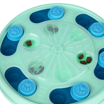 Round green feeding toy with blue paw covers and compartments, filled with dry food pieces. Encourages slow eating through interactive use.