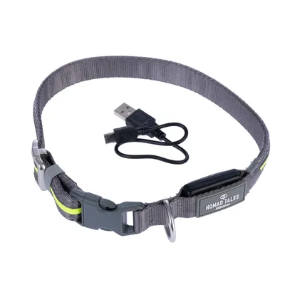 Collier gris en tissu avec boucle plastique, anneau métallique, étiquette Nomad Tales, câble USB inclus. Marquage visible : Nomad Tales Munich.