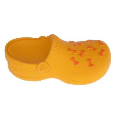 Juguete para perro amarillo en forma de zapato con patrones de huesos naranjas y detalle de huella.