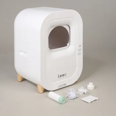 Kooa automatic cat house with accessories: power supply, filter, wheels and spare parts. White design with wooden legs and side controls.