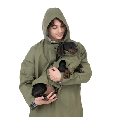 Person in olivgrünem Regenmantel hält einen Hund, der ebenfalls einen passenden olivgrünen Mantel trägt.