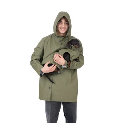 Grüne Regenjacke mit integriertem Hundetragefach, geeignet für kleine Hunde. Person hält einen kleinen Hund in der Jacke.