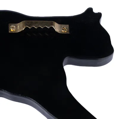 Parte trasera de una figura negra con forma de animal, muestra un colgador metálico dorado fijado con dos tornillos para montaje en pared.